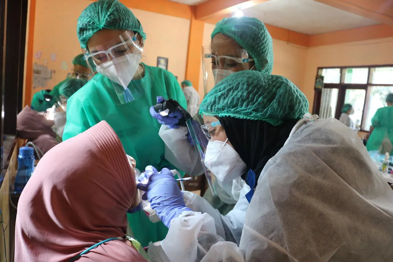 Volunteers wearing protective equipment working together during the dental outreach program.